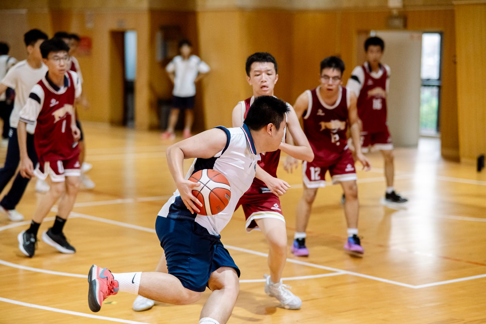 Teenagers playing a game of basketball in a school gym