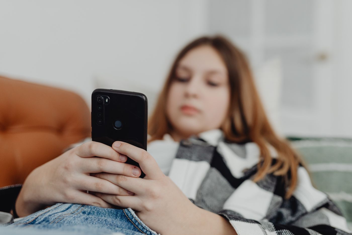 A teenager on a couch scrolling on a phone