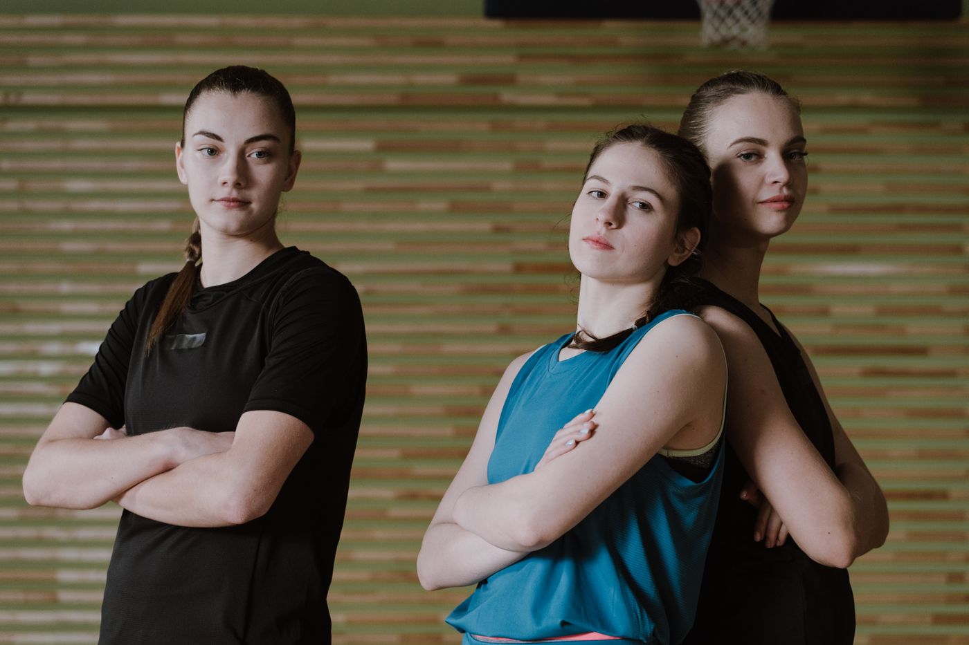 Three teenage girls in sports clothes on an indoor court